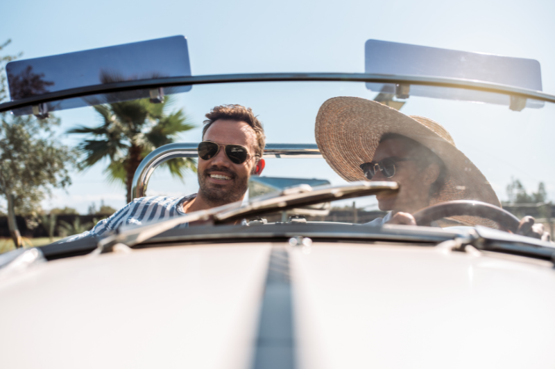 Pareja con su coche descapotable en la playa