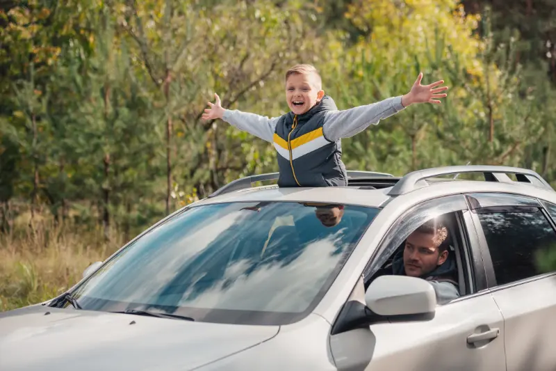 Niño feliz sonriendo desde el coche con techo solar